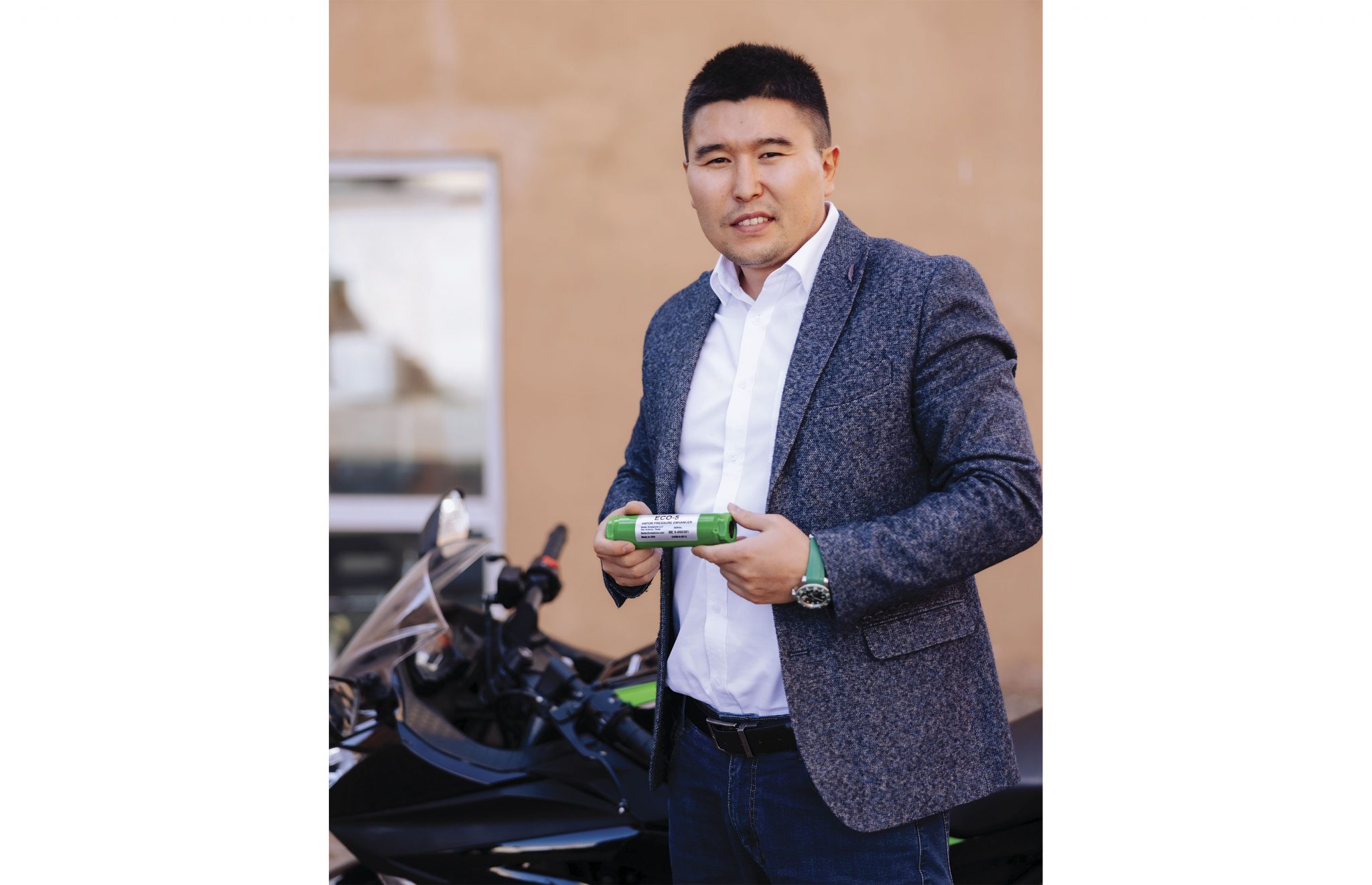 Цагаан цамц, жинсэн өмд дээр саарал пиджак өмссөн богино хар үстэй эр хар мотоциклийн хажууд зогсож байна. Тэрээр гартаа ногоон зүйл барьж байгаа бөгөөд магадгүй бизнесийнхээ савласан бүтээгдэхүүн байж магадгүй юм. Энтрепренер камер руу инээмсэглэв. - Business.MN