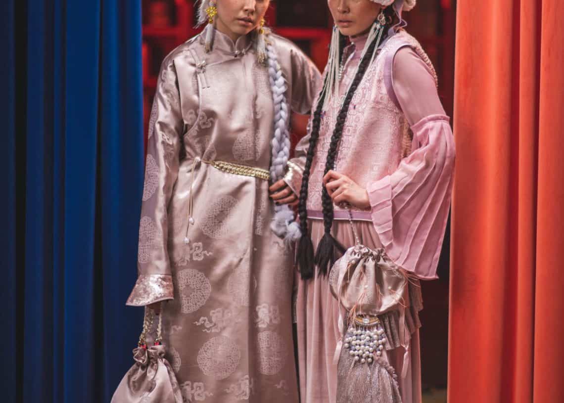 Улаан, цэнхэр өнгийн хөшиг бүхий тансаг орчинд хоёр хүн хамтдаа зогсоно. Хоёулаа хээнцэр, цайвар ягаан өнгийн хувцас, нарийн хийцтэй, металл мөнгөлөг гутал өмсдөг. Амжилттай энтрепренер шиг харагдаж байгаа нэг хүн үслэг малгай өмсөж, ирмэгийн гоёл чимэглэлтэй, нөгөө нь сүлжсэн, жижиг түрийвчтэй байдаг. - Business.MN