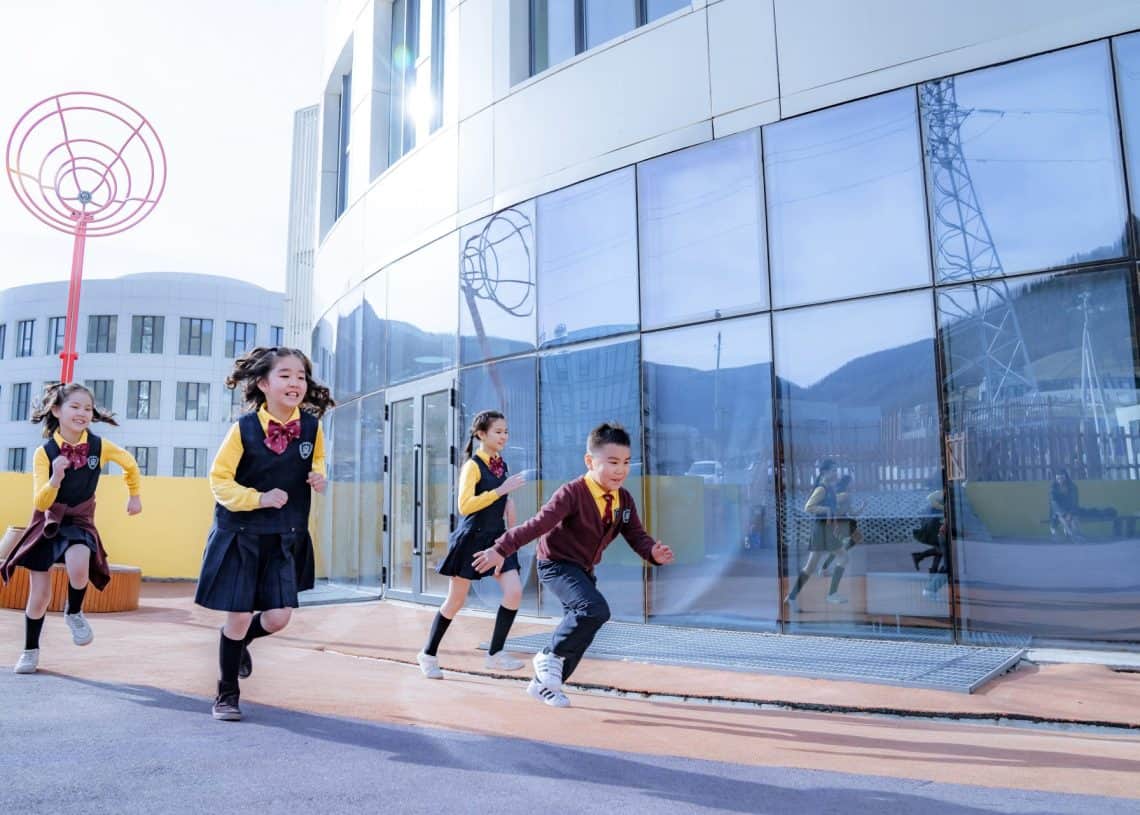 Сургуулийн дүрэмт хувцастай дөрвөн хүүхэд том цонхтой орчин үеийн барилгын дэргэд гадаа гүйж, инээмсэглэж байгаа нь ирээдүйн бизнес эрхлэгчид шиг харагдаж байна. Энэ бол гэрэлт, нарлаг өдөр бөгөөд сэтгэл санаа нь баяр хөөртэй, эрч хүчтэй байдаг. - Business.MN