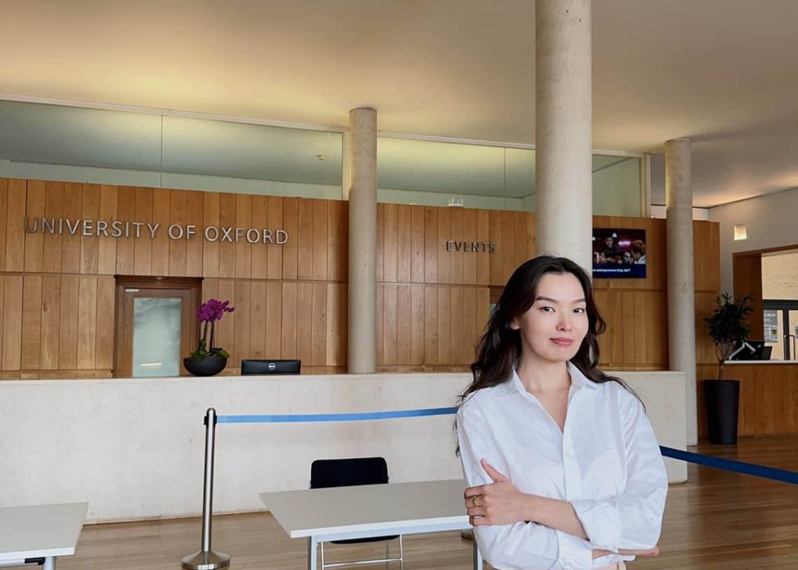 Гэрэл гэгээтэй, орчин үеийн үүдний танхимд хүн гараа зөрүүлэн зогсож байна. Арын дэвсгэр нь модон хавтан, "Оксфордын их сургууль", "Үйл явдал" гэсэн бичээс бүхий урлагийн уур амьсгалыг шингээдэг. Сандал бүхий хоёр ширээг урд талд байрлуулж, хөдөлгөөнт хэлэлцүүлгийг зохион байгуулахад бэлэн байна. - Business.MN