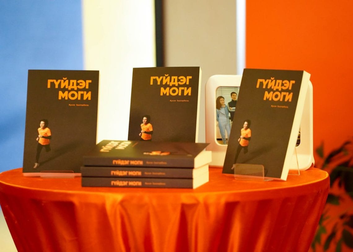 Several copies of a book with a black cover and yellow Ж.Баатарболд: Үгүй гэж хэлж сурснаар амьдралаа өөрчилсөн