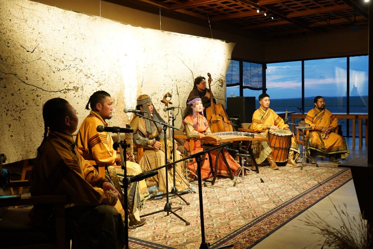 Үзэсгэлэнт цонхоор нар жаргахын эсрэг соёлын өвийг хуваалцаж, халуун дулаан гэрэлтүүлэгтэй тасалгааны орон зайд уламжлалт хувцастай хөгжимчид янз бүрийн хөгжмийн зэмсгээр тоглож, тогтвортой аялал жуулчлалыг сурталчилж байна. - Business.MN