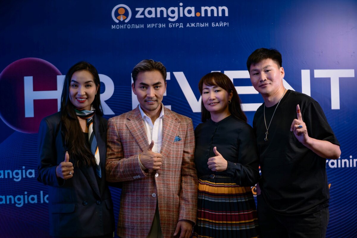 Цэнхэр "zangia.mn" хүний нөөц HR EVENT фонны өмнө ажил хэрэгч, ухаалаг энгийн хувцас өмссөн дөрвөн хүн инээмсэглэн, эрхий хуруугаа өргөөд зогсоно. - Business.MN