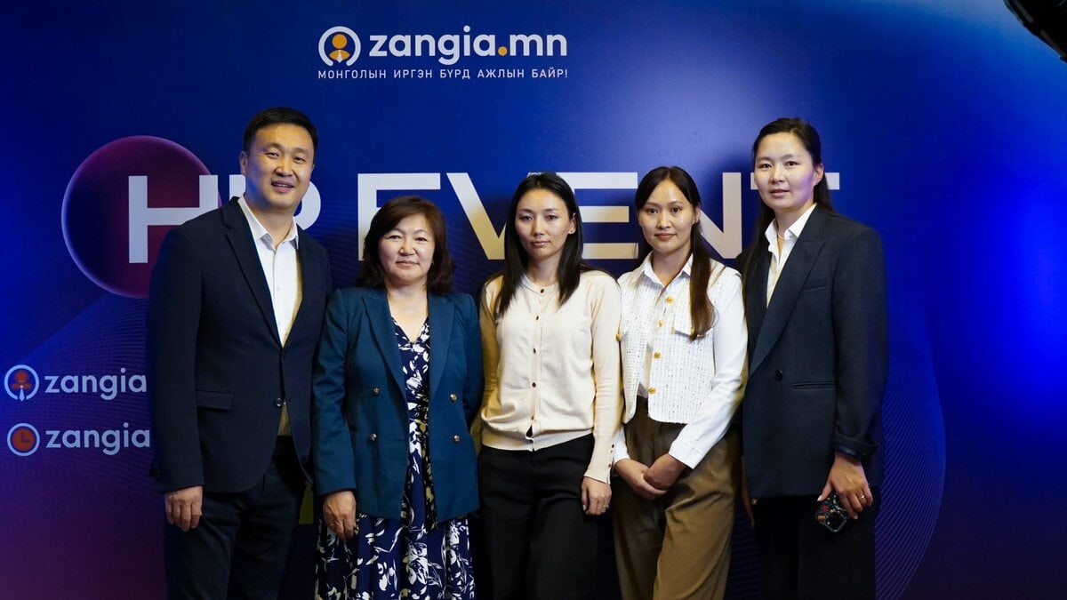 Хүний нөөцийг илэрхийлсэн "zangia.mn" болон бусад бичвэр бүхий цэнхэр дэвсгэрийн өмнө таван хүн хамтдаа инээмсэглэн зогсож байна. Тэд ажил хэрэгч эсвэл ухаалаг энгийн хувцас өмссөн байдаг. - Business.MN