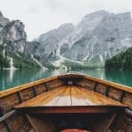world travel on a budget brown wooden boat moving towards the mountain
