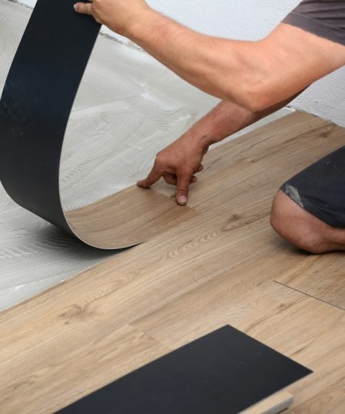 Worker installing new vinyl tile floor Worker installing new vinyl tile floor
