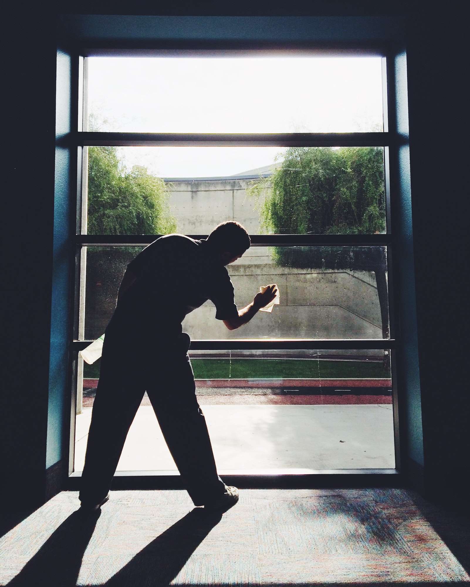 A man cleans a window using cleaning supplies to stop the spread of Covid-19 coronavirus.