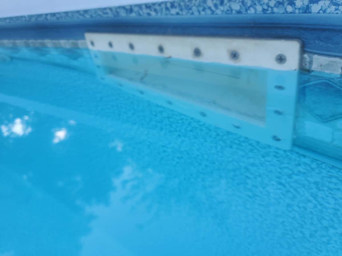 Pool water is over full covering a pool skimmer.