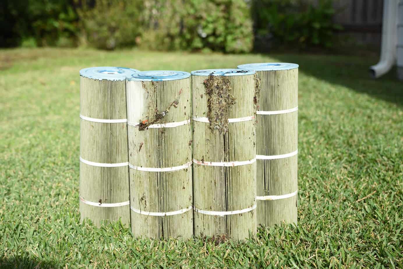 4 dirty cartridge filters on the grass.