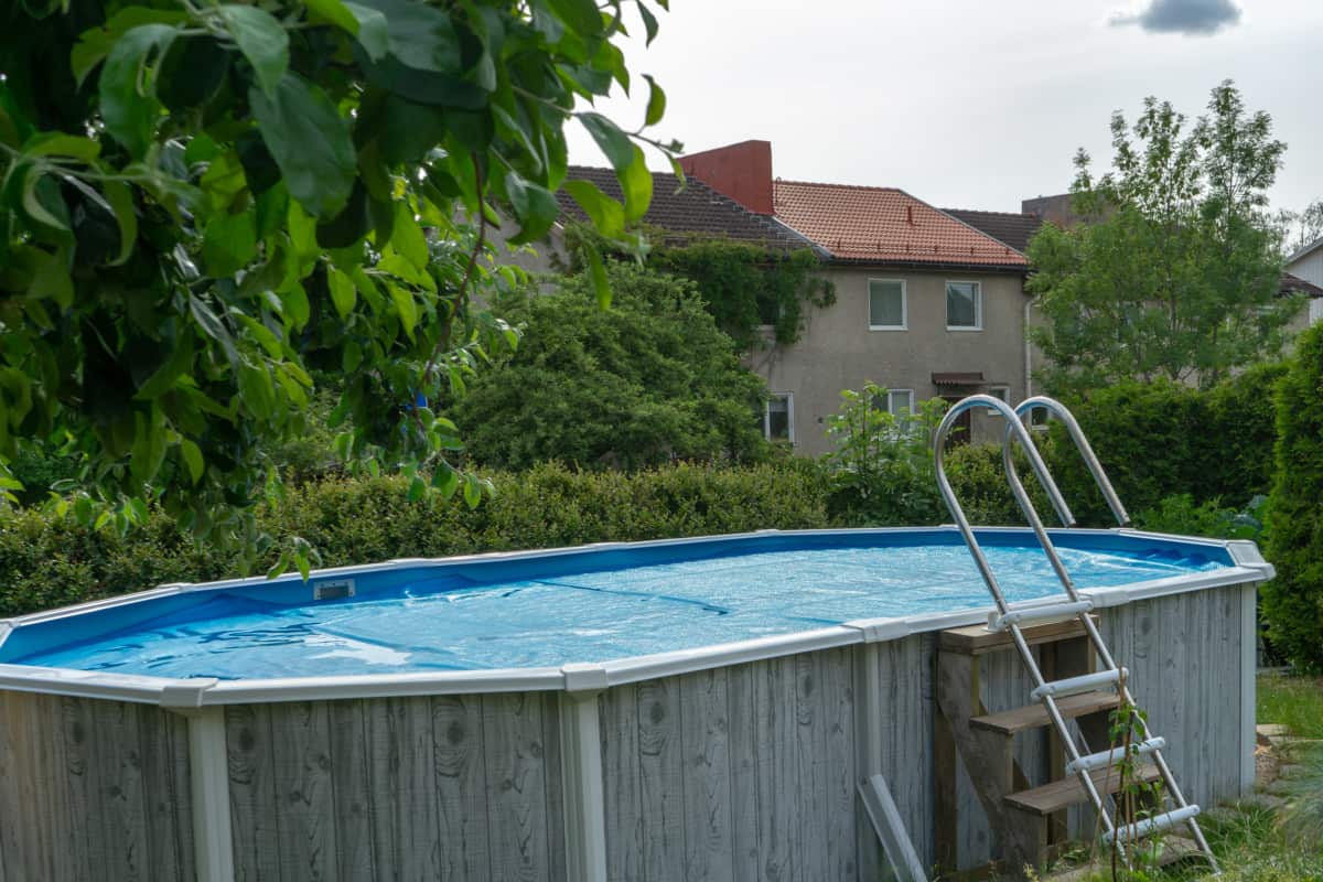 An above ground swimming oval shaped pool filled with clear water.