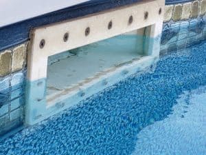 Pool skimmer at the surface water.