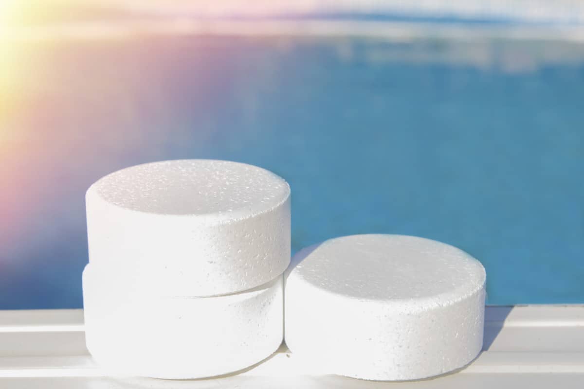 3 chlorine tablets sitting on the side rail of a swimming pool.