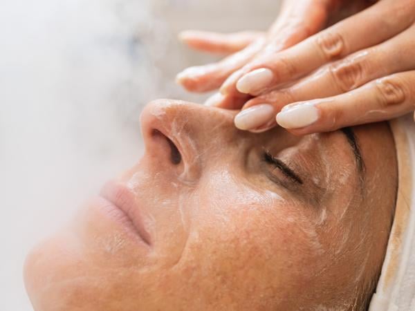 Profesional de la cosmetología aplicando tratamiento con vaporizador facial