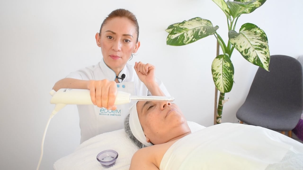 Profesional ajustando el electrodo de fulguración en el maneral del aparato de alta frecuencia.