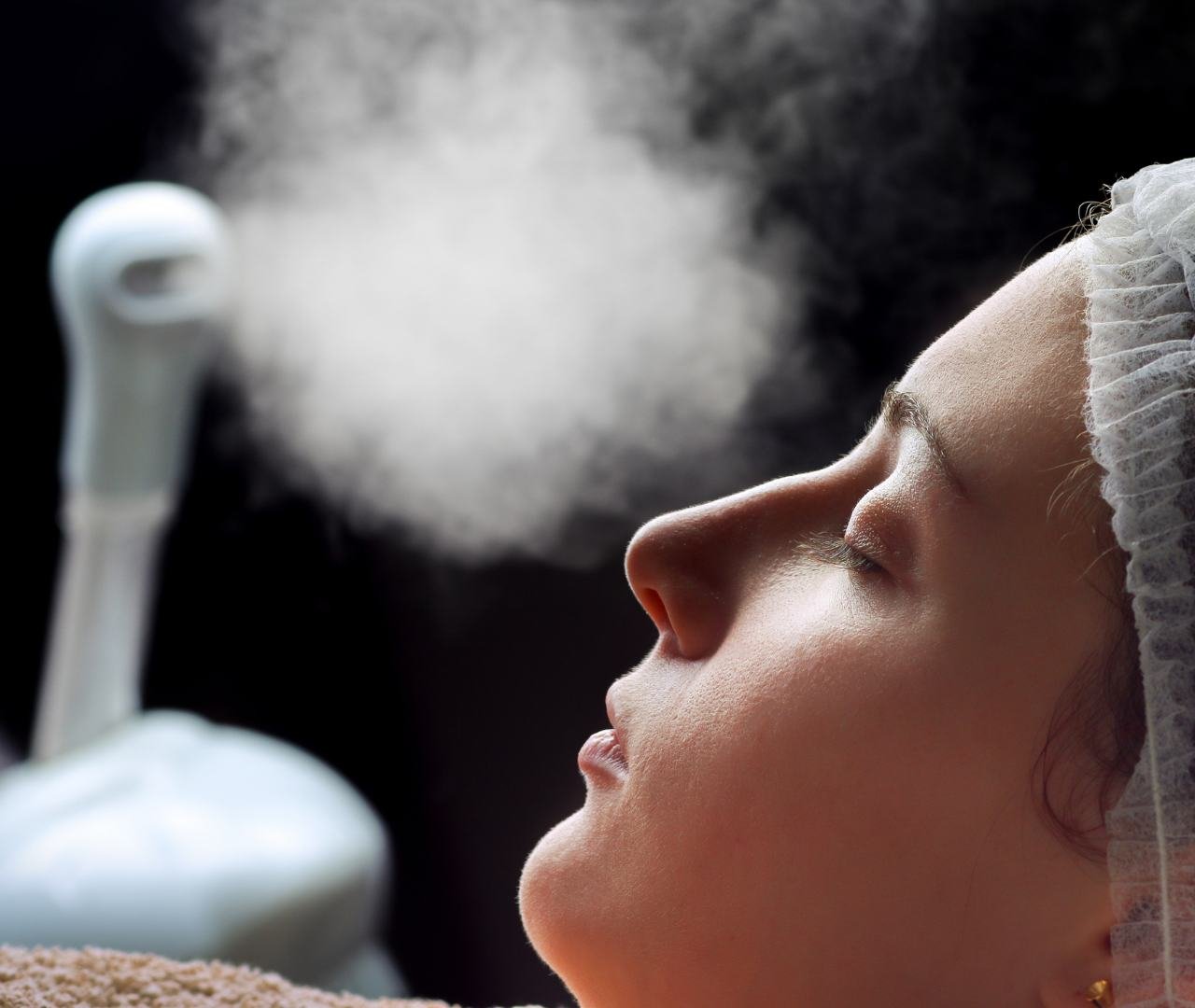 Profesional de la cosmetología aplicando tratamiento con vaporizador facial