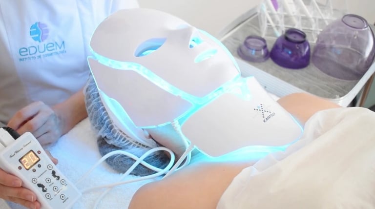 Máscara LED configurada en color cian para prevenir signos de envejecimiento en pieles jóvenes.