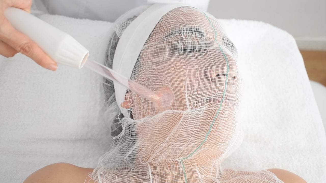 Profesional aplicando tratamiento facial con alta frecuencia en piel sensible.