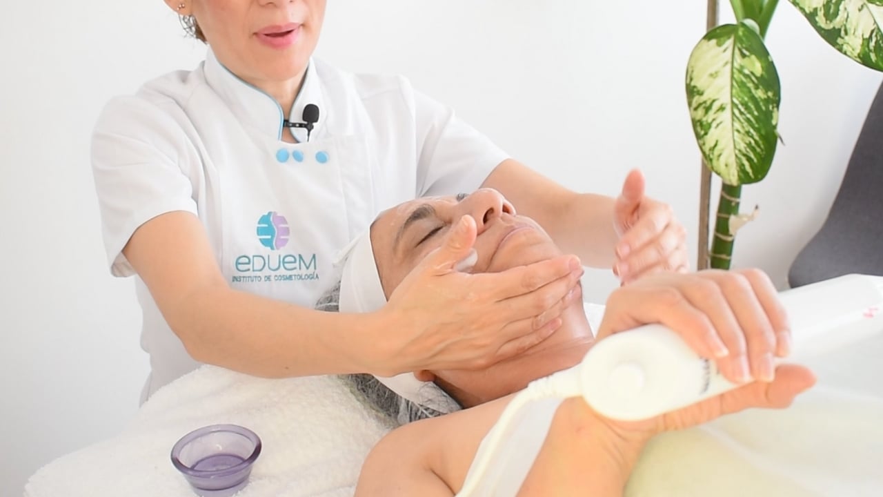 Profesional realizando lisajes largos con el masaje facial de alta frecuencia para distribuir el producto.