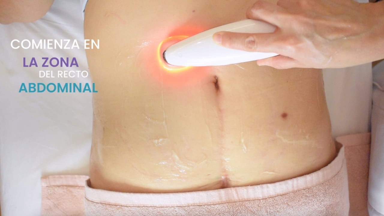 Profesional aplicando electroestimulación en el abdomen de una clienta en un spa.