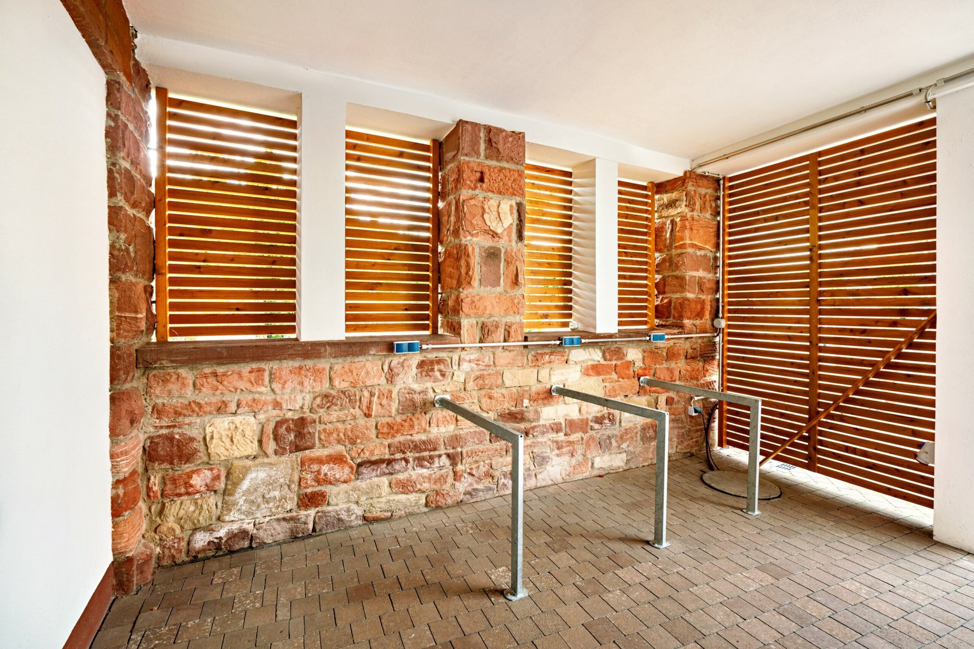 MainZauber Apartments Miltenberg am Main - Erleben Sie den perfekten Urlaub in unserem Luxusapartment. Diese exquisite Unterkunft verfügt über atemberaubende Designelemente, darunter Stein- und Holzlamellenwände, in denen sich elegante Fahrradständer aus Metall auf einem charmanten Ziegelsteinboden befinden. Das Apartment ist in natürliches Licht getaucht, das durch die Holzlamellen strömt und eine warme und einladende Atmosphäre schafft. Egal, ob Sie einen ruhigen Rückzugsort oder einen abenteuerlichen Ausflug suchen, dieses Ferienapartment bietet die ideale Mischung aus Komfort und Stil für Ihren Aufenthalt.