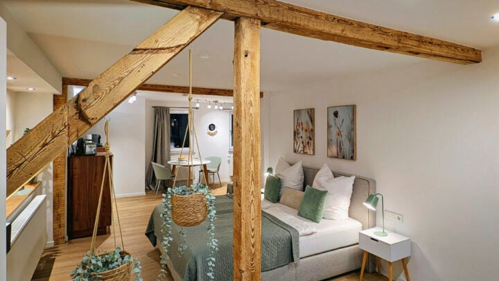 MainZauber Apartments früher MainTerrasse Miltenberg am Main - Entdecken Sie das ultimative Ferienwohnungserlebnis in diesem gemütlichen, modernen Dachgeschoss-Refugium. Dieses luxuriöse Urlaubsapartment ist perfekt für Ihren nächsten Kurzurlaub und verfügt über ein charmantes Schlafzimmer mit freiliegenden Holzbalken, die Charakter und Wärme ausstrahlen. Entspannen Sie sich auf dem bequemen Doppelbett mit eleganter grün-weißer Bettwäsche, umgeben von durchdachten Details wie zwei Nachttischen mit schicken Lampen. Genießen Sie Mahlzeiten in Ihrem intimen Essbereich inmitten von Hängepflanzen, die Ihrer Unterkunft einen Hauch von Natur verleihen. Die sanfte Beleuchtung im gesamten Apartment schafft eine ruhige Atmosphäre, in die Sie nach der Erkundung Ihres Reiseziels gerne zurückkehren werden. Erleben Sie unvergleichlichen Komfort in diesem exquisiten Ferienapartment!