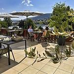 MainZauber Apartments Miltenberg am Main - Stellen Sie sich vor, Sie entspannen sich in einer Ferienwohnung und genießen einen entspannten Morgen auf der sonnigen Außenterrasse. Diese luxuriöse Unterkunft verfügt über Sonnenschirme und Topfpflanzen und schafft so eine einladende Atmosphäre für Ihren Urlaub. Die Aussicht bietet einen atemberaubenden Blick auf einen malerischen Fluss und üppige Hügel unter einem klaren blauen Himmel mit flauschigen Wolken. In der Nähe sind charmante Tische elegant mit Tabletts und Blumen gedeckt und unterstreichen die ruhige Atmosphäre Ihres perfekten Urlaubsdomizils.