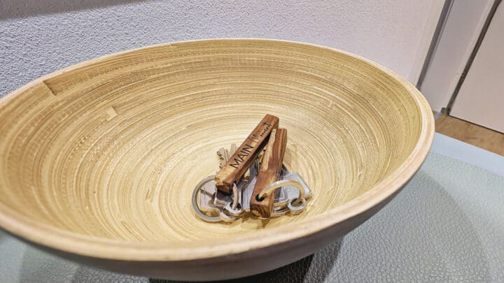 MainZauber Apartments früher MainTerrasse Miltenberg am Main - Entdecken Sie Ihr ideales Luxus-Ferienapartment, in dem jedes Detail auf Ihren Komfort und Ihre Bequemlichkeit zugeschnitten ist. Stellen Sie sich vor, Sie betreten eine wunderschön eingerichtete Unterkunft und werden von einer Holzschale begrüßt, die elegant auf einer Glasoberfläche steht. Darin finden Sie die Schlüssel zu Ihrem perfekten Rückzugsort, die jeweils an einem fein gearbeiteten hölzernen Schlüsselanhänger mit der Aufschrift „MAIN“ befestigt sind. Genießen Sie die Ruhe, zu wissen, dass Sie an einem exquisiten Ziel angekommen sind, das zum Entspannen und Genießen konzipiert wurde.