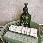 Entdecken Sie die perfekte Ferienwohnung mit allem Komfort von zu Hause! Diese luxuriöse Unterkunft bietet Liebe zum Detail, wie einen charmanten grünen Korb, in dem sich zwei makellose Küchentücher befinden – eines mit dem fröhlichen Wort „LOVELY“ und ein anderes mit stilvollen Streifen. Eine grüne Pumpflasche mit der Aufschrift „Spülmittel“ steht bequem für Ihren Gebrauch bereit und verschönert Ihren Aufenthalt. Vor einer wunderschön gefliesten Wand machen diese durchdachten Details diese Ferienwohnung zur idealen Wahl für einen erholsamen Kurzurlaub. - MainZauber Apartments Miltenberg am Main