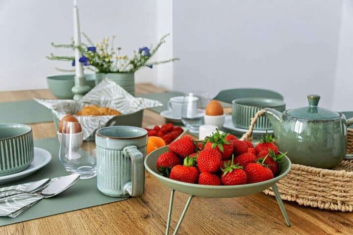 MainZauber Apartments früher MainTerrasse Miltenberg am Main - Frühstückstisch im Luxus-Apartment AltstadtZauber Miltenberg mit grünem Geschirr, Croissants, Obst - perfekte Unterkunft.