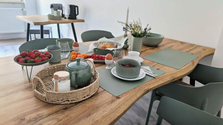 MainZauber Apartments früher MainTerrasse Miltenberg am Main - Luxuriöse Ferienwohnung in der Altstadt: Frühstückstisch mit frischen Früchten, Brot, Tee und stilvoller Einrichtung.