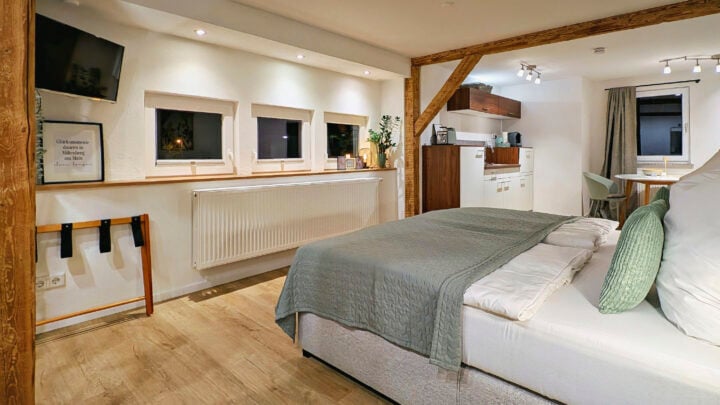 MainZauber Apartments früher MainTerrasse Miltenberg am Main - Entdecken Sie die perfekte Ferienwohnung für Ihren nächsten Urlaub – dieses gemütliche, moderne Studio bietet alles, was Sie für einen erholsamen Aufenthalt brauchen. Erleben Sie den Charme einer Luxusunterkunft mit schönen Holzbalken und einladender Atmosphäre. Das Apartment verfügt über ein ordentlich gemachtes Bett mit grünen Kissen und einer passenden Decke, die erholsame Nächte garantieren. Genießen Sie Mahlzeiten am kleinen Esstisch oder bereiten Sie Ihre Lieblingsgerichte in der kompakten Küche zu. Entspannen Sie sich, während Sie Ihre Lieblingssendungen auf dem an der Wand montierten Fernseher ansehen, und lassen Sie natürliches Licht durch drei kleine Fenster strömen, wodurch Dekorelemente wie leuchtende Pflanzen und gerahmte Kunst hervorgehoben werden. Tauchen Sie ein in diesen eleganten Rückzugsort und erleben Sie einen unvergesslichen Urlaub!
