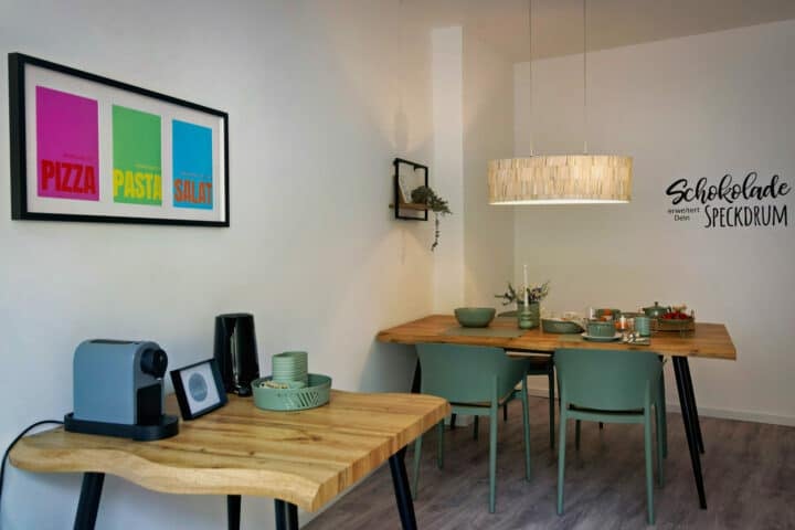 MainZauber Apartments früher MainTerrasse Miltenberg am Main - Luxuriöse Ferienwohnung in Miltenberg: Moderner Essbereich mit Holztischen, Kaffeemaschine & stilvoller Ausstattung.