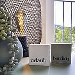 Entdecken Sie die perfekte Ferienwohnung für Ihren nächsten Urlaub! Stellen Sie sich vor, Sie entspannen sich in einem Luxusapartment, umgeben von durchdachten Details, in denen Sie sich wirklich wie zu Hause fühlen. Stellen Sie sich zwei charmante Holzklötze mit der Aufschrift „Urlaub“ und „herzlich“ vor, die einen warmen Ton auf Ihrem gemütlichen, hellblauen Tisch erzeugen. Ihre Unterkunft bietet einzigartige Details wie eine moderne schwarze Netzlampe, die neben einer erfrischenden Sukkulente leuchtet, während ein Fenster mit Blick auf üppiges Grün Ihre ruhige Umgebung bereichert. Buchen Sie dieses außergewöhnliche Luxusapartment noch heute für ein unvergessliches Urlaubserlebnis! - MainZauber Apartments Miltenberg am Main