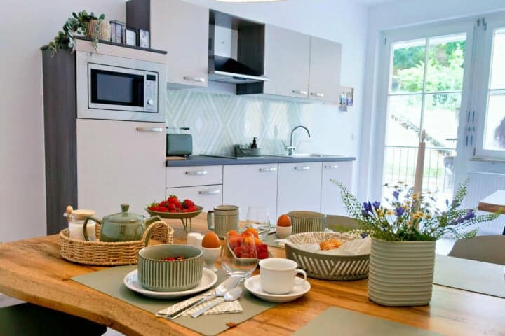 MainZauber Apartments früher MainTerrasse Miltenberg am Main - Luxuriöse Ferienwohnung mit moderner Küche, Frühstückstisch und Panoramablick ins Grüne im Herzen der Altstadt Miltenberg.