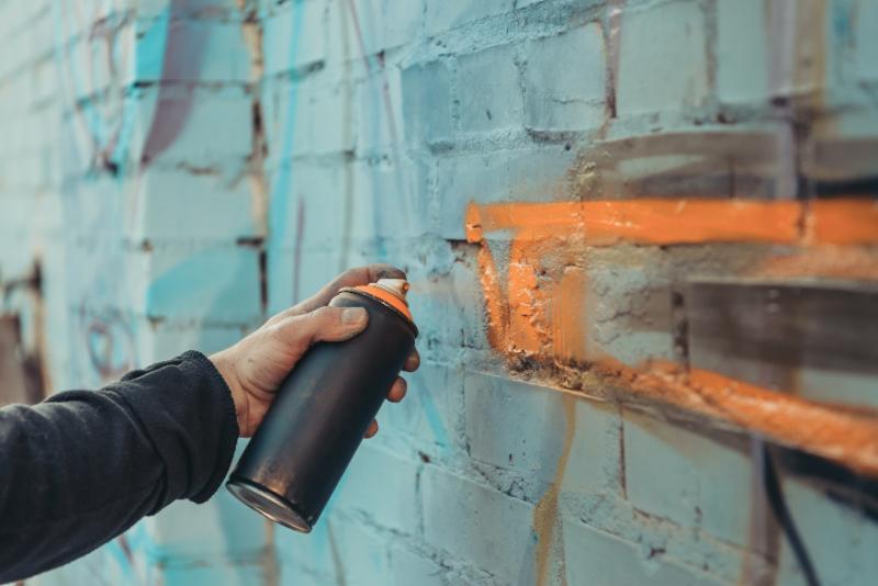 person spraying graffiti on a brick wall