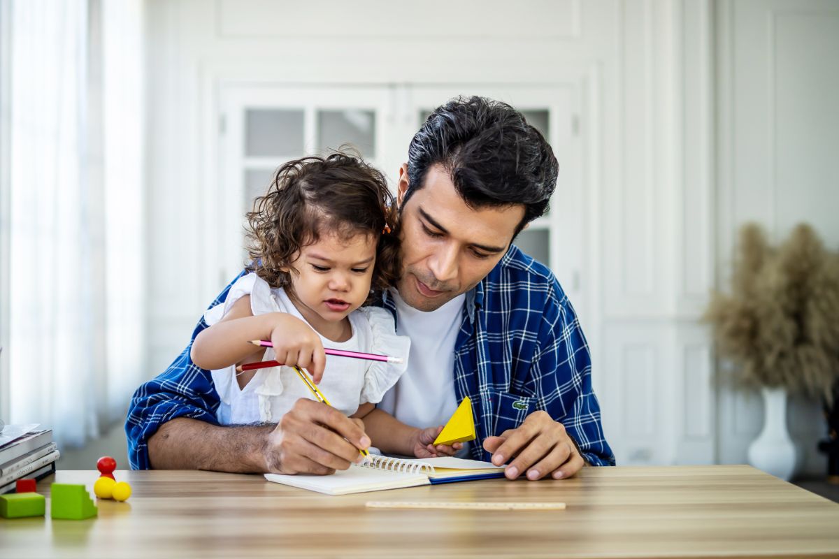 father teaching his daughter at a table