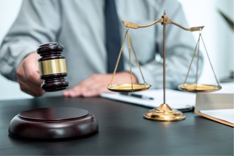 chest down view of person at desk with justice scales on desk and gavel