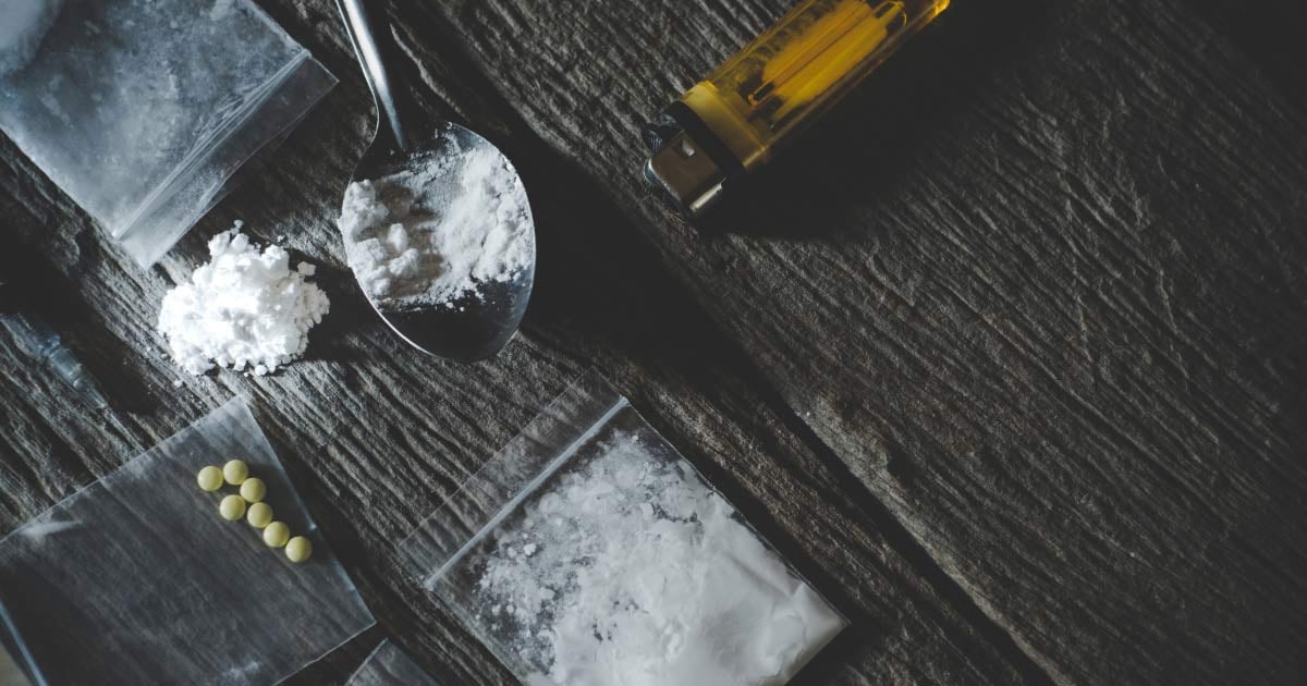 Spoon and baggies with drugs and lighter on table