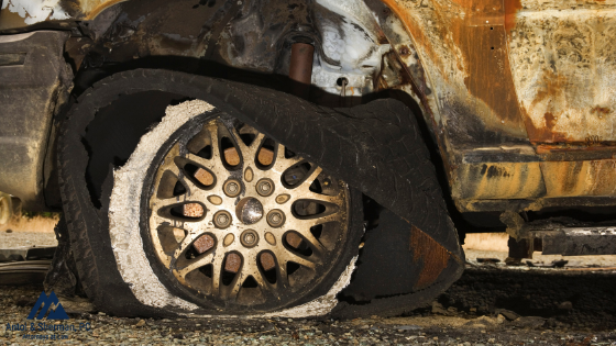 Close up of a vehicle after a accident with burn marks and a blown out tire.