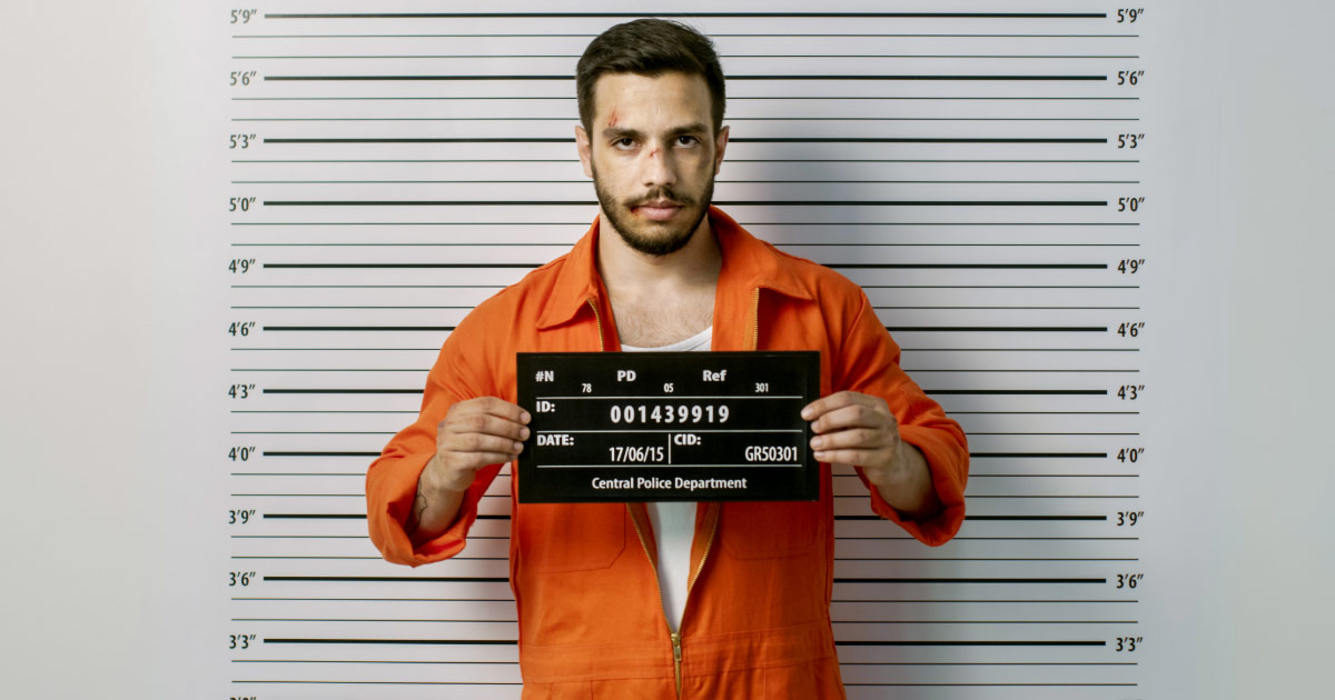 Man getting mugshot taken wearing orange jumpsuit