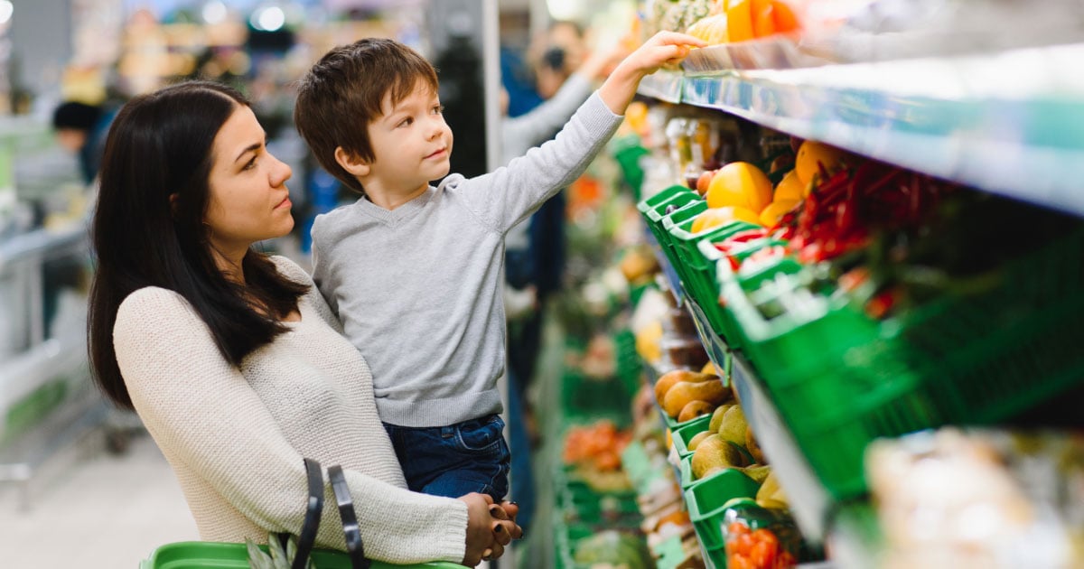 Woman holding her son while shopping in grocery store