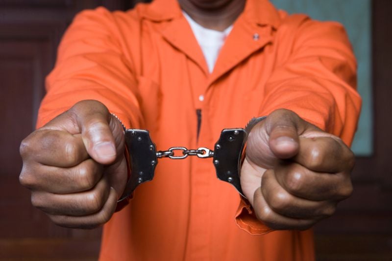 neck to chest POV of man in orange jumpsuit with handcuffs