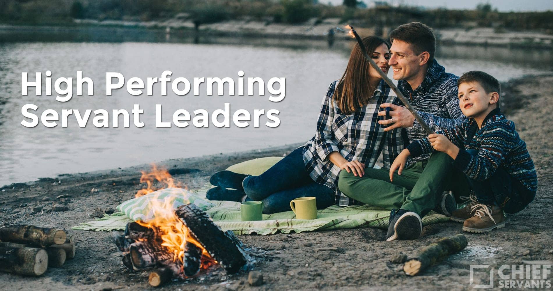 A smiling family of three sits by a lakeshore campfire roasting marshmallows, embodying servant leadership. They relax on a green blanket with mugs beside them. The text “High Performing Servant Leaders” is overlaid. Logo bottom right reads "Chief Servants.