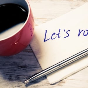 Cup of coffee and napkin with writings on table