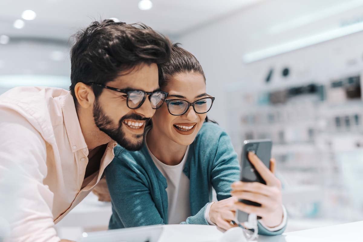 Una pareja revisando un celular en una tienda, representando a un cliente ideal.