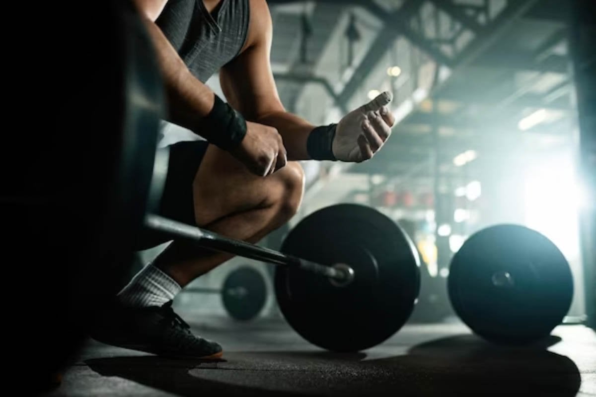 Un hombre se agacha con una barra delante de él en un gimnasio.