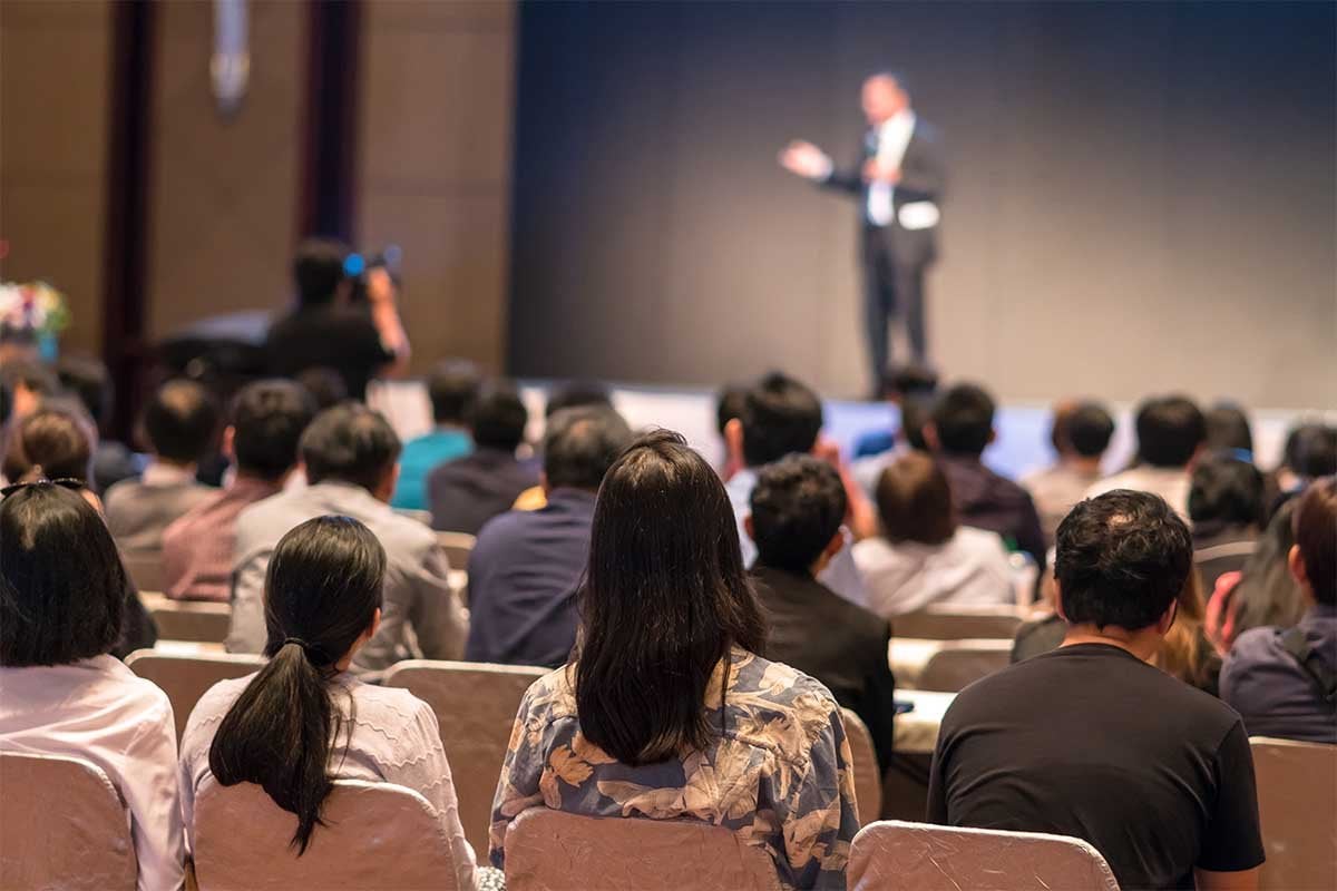 Un hombre está dando una presentación de estrategias de negocios a un grupo de personas en un auditorio.