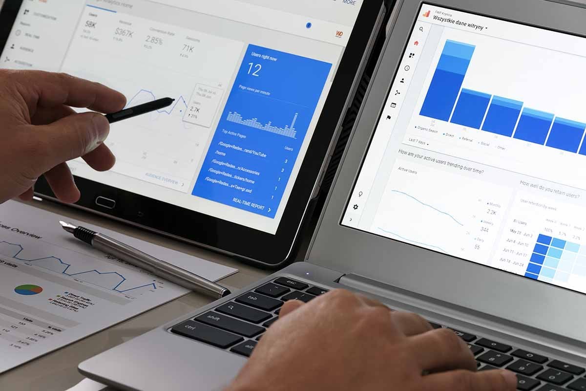 Dos computadoras portátiles que muestran gráficos de Google Analytics para métricas de anuncios de Facebook.