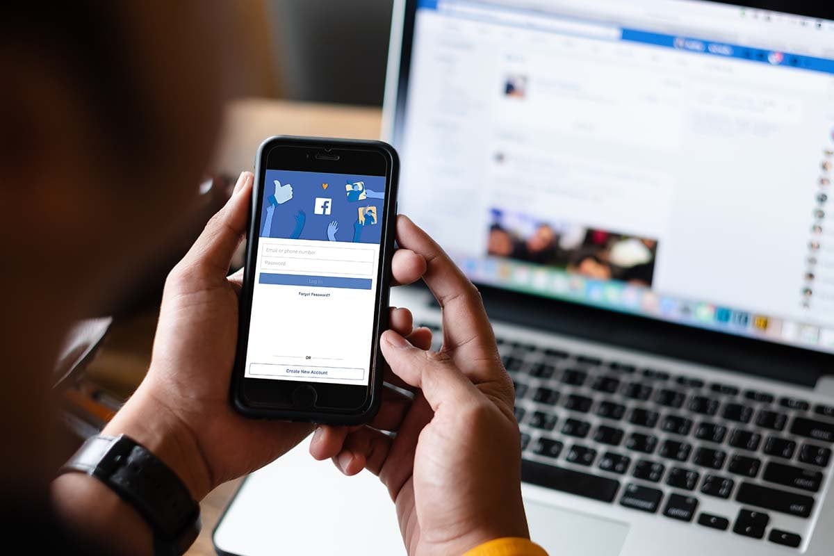 Una persona que sostiene un teléfono celular que muestra anuncios de Facebook.