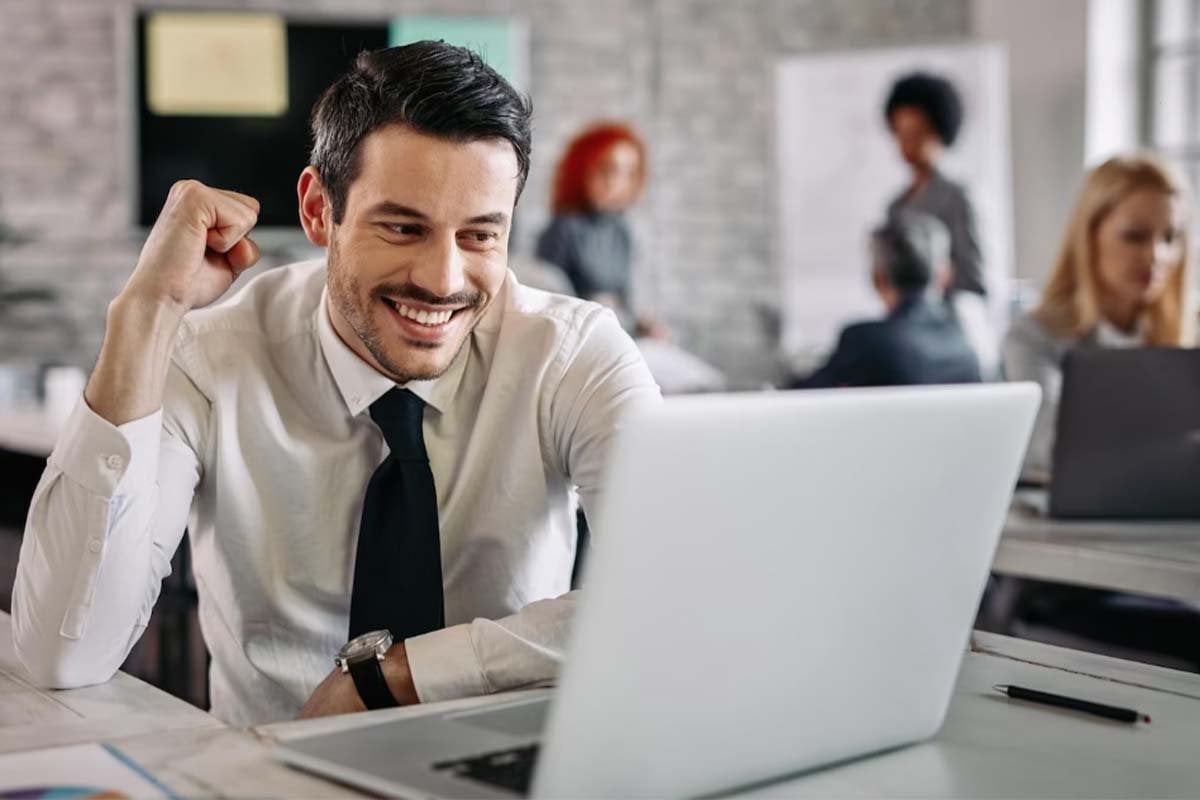 Un hombre con traje de negocios está felizmente trabajando en una computadora portátil, invirtiendo en anuncios de Facebook.